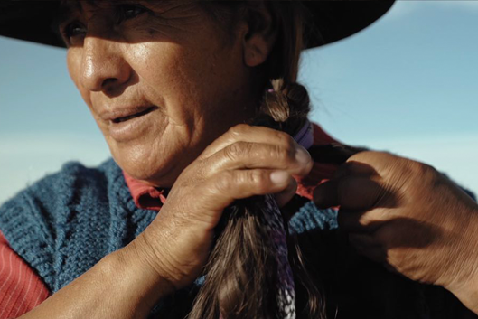 an indigenous woman braids her hair